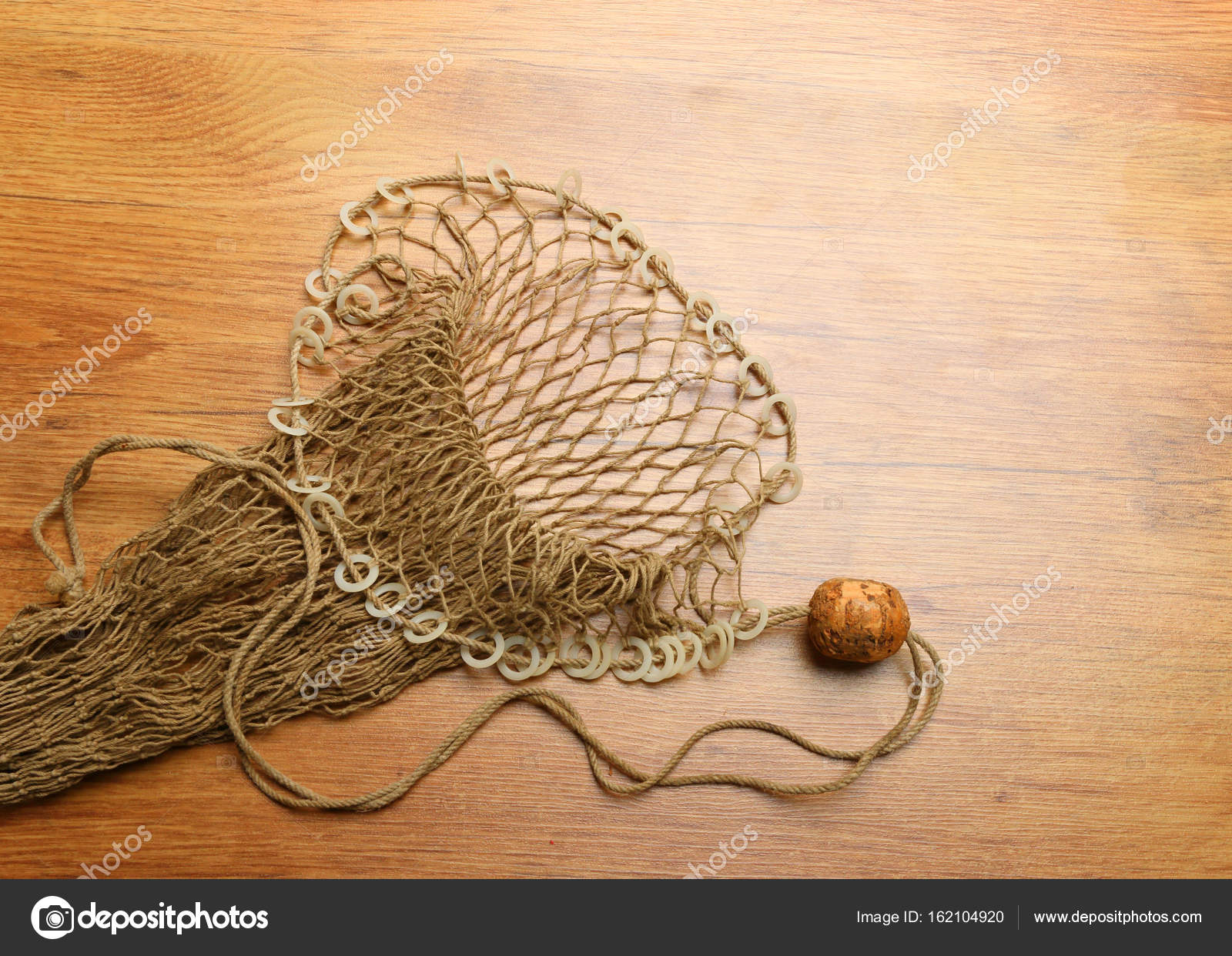 Fishing net with cork buoy on wooden plate Stock Photo by