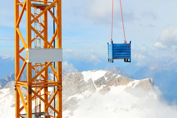 Crane with load on Germany's highest construction site in 2962m. Building the new Zugspitze cable car for tourists and skiers.