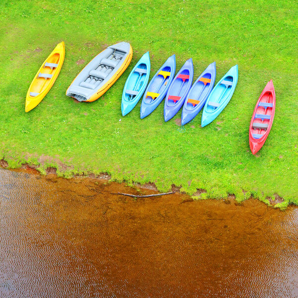 Canoes and raft on a lake shore. Aerial view of place for leisure activities. Happy vacations in wilderness area.