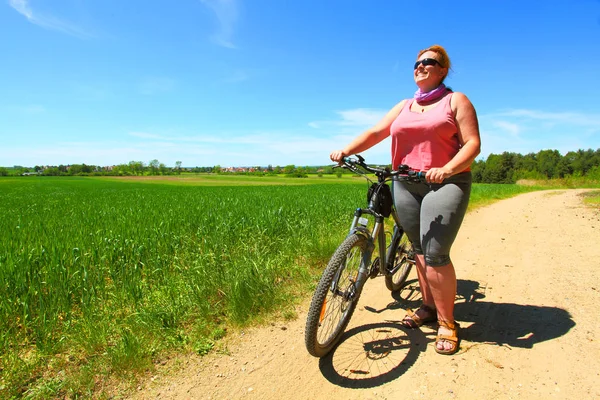 骑自行车的超重妇女 积极的人在乡下享受暑假 — 图库照片