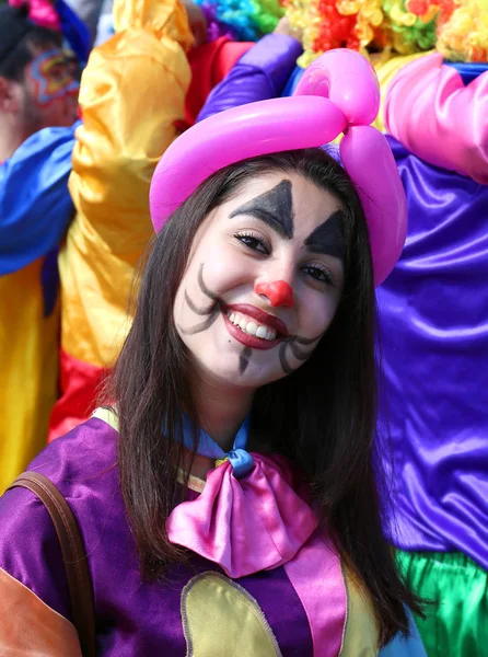 身份不明的女孩小丑着大大的笑容，构成在橙色开花嘉年华 — 图库照片