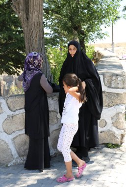 Ihlara Vadisi girişine yakın duran bir çocuk ile tanımlanamayan dini kadın. 22 Temmuz Ihlara Vadisi, Aksaray, Türkiye.