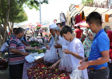 Uzbek and Afghan immigrants buying red plums at the farmers market clipart