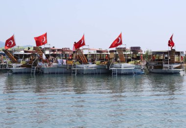 Iztuzu Plajı'nda turistler için bekleyen Türk bayraklarıyla tur tekneleri