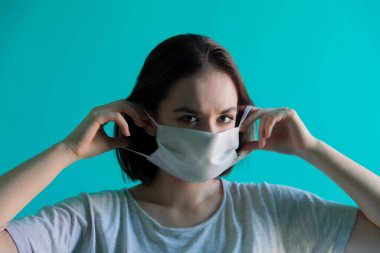Beyazlı bir kız tıbbi maske takıyor.