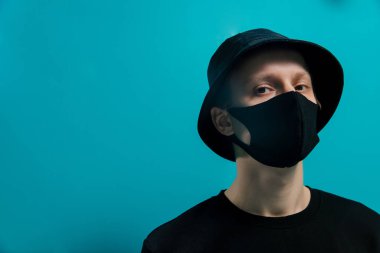 Siyah tıbbi maskeli, kova şapkalı ve siyah ceketli adam...