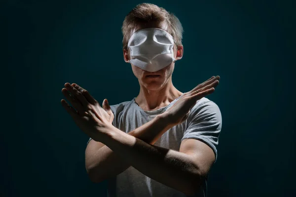 the guy with the medical mask over his eyes, against fake news in a dark room with dramatic light, rejection, gesture