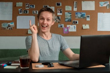 Adam masasında oturuyor, bir dizüstü bilgisayar üzerinde çalışıyor ve yeni fikirden memnun.