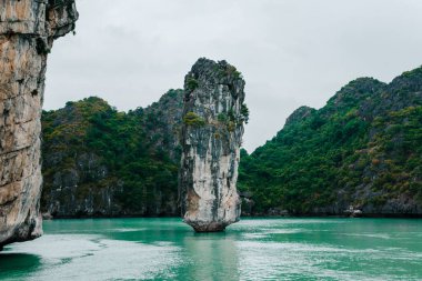 Güney Çin Denizi 'nin Ha Long Körfezi' ndeki kayaların ve yerel balıkçı teknesinin manzarası. Ha Long Körfezi Asya 'nın popüler bir turizm merkezidir..