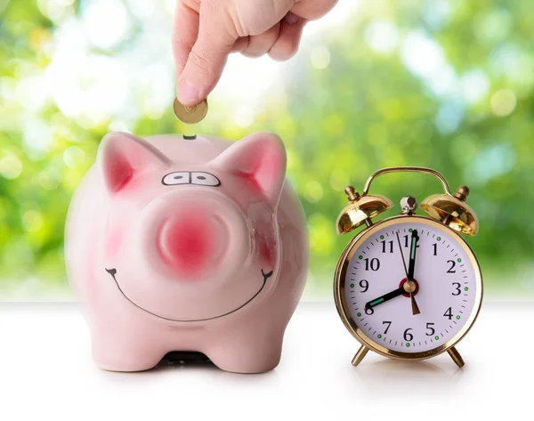 Coin in piggy bank with retro alarm clock