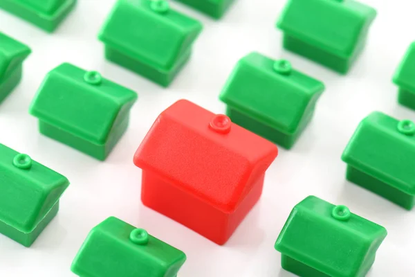 Grande casa vermelha que se destaca de pequenas casas verdes — Fotografia de Stock