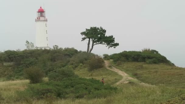 Pessoas caminhando para o farol na colina Dornbusch, na Ilha Hiddensee, na Alemanha. Hora do Outono . — Vídeo de Stock