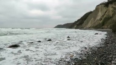 Flint taş fosil aramaya Cape beach Arkona boyunca yürüyüş insanlar. Sonbahar hava ve dalgalar. (Rügen Adası, Almanya)