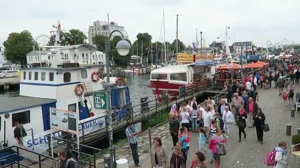 WARNEMUENDE, Mecklenburg-Vorpommern/ GERMANY AUGUST 13 2016: Hansesail in Warnemuende and Rostock harbor People walking along promenade at warnow river. — Stock Video