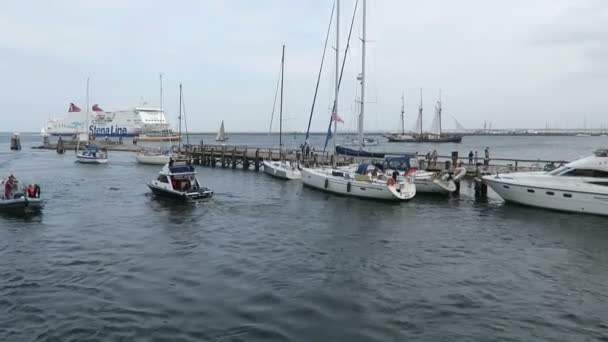 WARNEMUENDE, Mecklenburg-Vorpommern/ GERMANY AUGUST 13 2016: small boats driving along the warnemuende harbor toward baltic sea. Hanse Sail event.  In background Scanline ferry leaving the port. — Stock Video