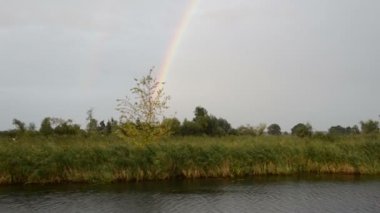 Havel Nehri boyunca bir tekne ile sürüş. Gökkuşağı (Brandenburg, Almanya) ile yağmur. Havelland.