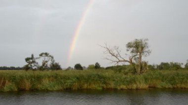 Havel Nehri boyunca bir tekne ile sürüş. Gökkuşağı (Brandenburg, Almanya) ile yağmur. Havelland.