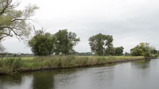 Driving with a boat along the havel river (Havelland, Germany). On shore of river willow tries and reed. start of autumn time. on left side village Schollene — Stock Video