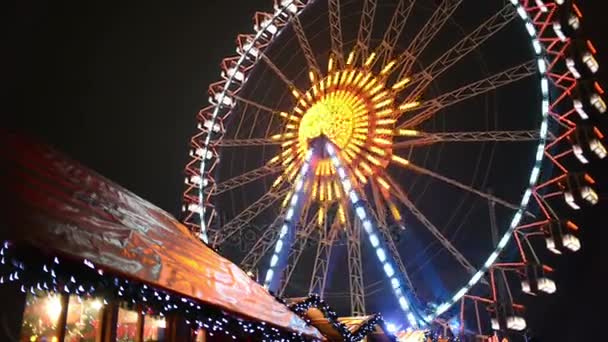 People visiting the xmas fair at alexanderplatz in berlin (germany). in front market stalls with food and craft items. ferries wheel in background — Stock Video