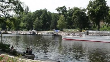 Turist tekne Brandenburg tarafından bir der Havel (Almanya) geçiyor. Ördek besleme kıyıda oturan insanlar.