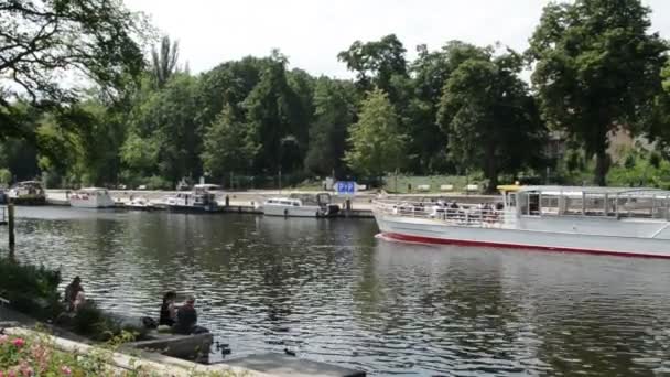 El barco turístico pasa por Brandenburg an der Havel (Alemania). Gente sentada en la orilla alimentando patos . — Vídeo de stock