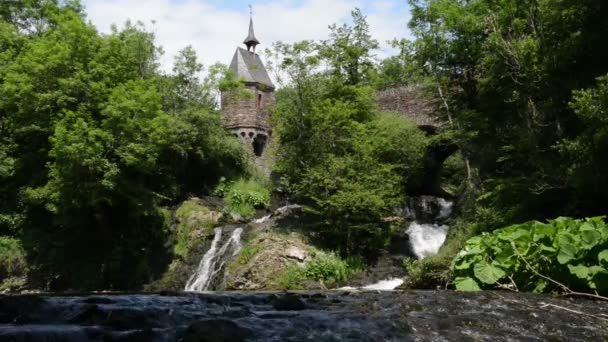 Cascada del río Elz con una pequeña iglesia en un puente y un antiguo molino de agua de madera. El río fluye a lo largo de la aldea Monreal y el castillo Burg Eltz. (Eifel, Alemania ) — Vídeos de Stock