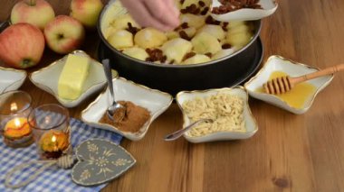 Elmalı pasta pişirme. Slivered badem ve kuru üzüm ham elma pasta serpilir. Ayrıca, bal, tarçın, şeker gibi maddeler vardır