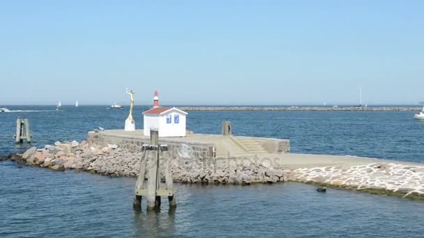 A entrada do porto de Warnemunde no Mar Báltico. No cais há uma pequena cabana com uma estátua e um farol . — Vídeo de Stock