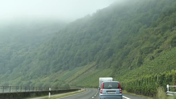 Conducir con un coche a lo largo de la región del río Mosel junto a Bremm (Alemania). campos y pueblo en el fondo. landscape.tractor delante . — Vídeos de Stock