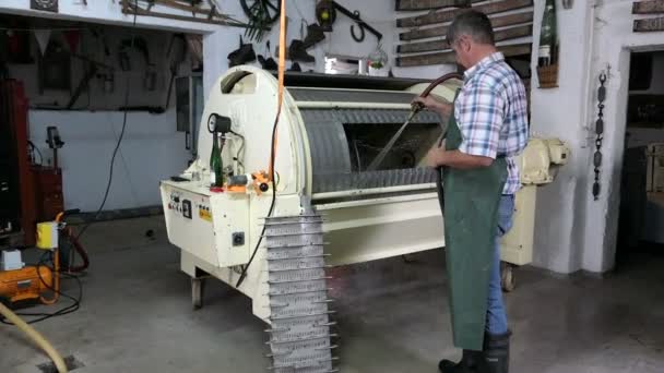 Granjero limpieza de una máquina de prensa de vino después de presionar las aberturas de vino blanco . — Vídeo de stock