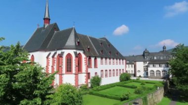 Bernkastel-Cuez, Rhineland-Palatinate / Almanya 30 Ağustos 2019: Cusanus Hastanesi Kilisesi ile Bernkastel-Cuez şehri. İnsanlar gezinti güvertesinde yürüyor.