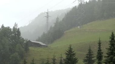 Avusturya Alplerinde yağmur havası. Büyük yağmur damlaları düşüyor. Arka planda geleneksel Tirol kulübesi.