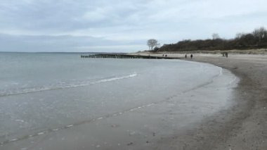 Ahrenshoop, Mecklemburg-Vorpommern / GERMANY - 15 Mart 2020: Almanya 'nın Mecklemburg-Vorpommern kentindeki Ahrenshoop köyünde Darss yarımadasının kıyı sahilinde yürüyen insanlar. Sazlı kum tepeleri.