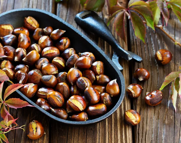 Roasted chestnuts on an old board. Selective focus. — Stock Photo, Image