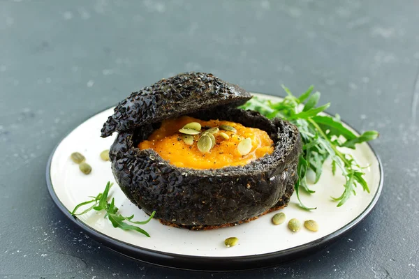 Pumpkin soup in a black bun for the holiday of Halloween. — Stock Image Pumpkin Soup Black Bun Holiday Halloween Royalty Free Stock Images
