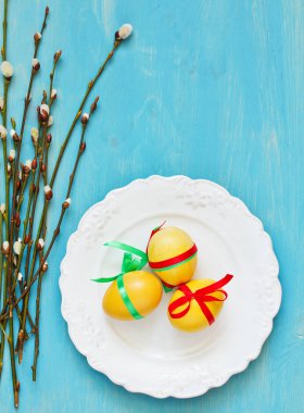 Mavi tahta üzerinde söğüt dallı Paskalya yumurtaları.