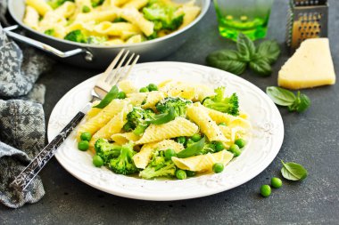 penne pasta with spinach pesto sauce, green peas and broccoli, top view clipart