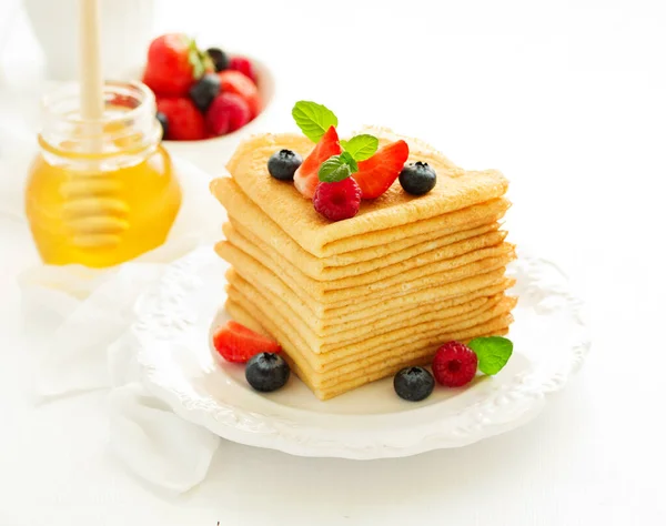 A pile of Russian-style pancakes with berries and honey for the carnival feast...
