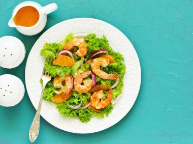 Marul, bir tabak turuncu, kırmızı soğan ve karides Salata sos ile dilim. Bir diyet yemek.