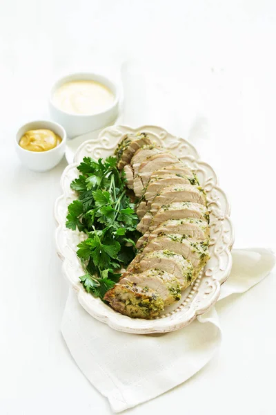 Baked pork tenderloin in herbs, with mashed potatoes and garnish.
