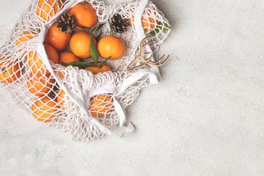 Eko noel konsepti, pamuk örgüsü içinde organik olgun mandalinalar.