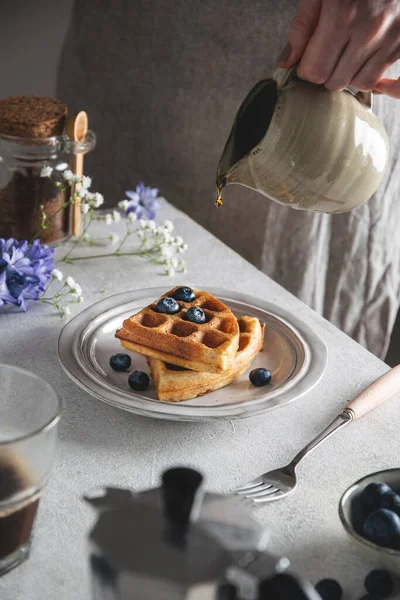 Gri masada taze pişmiş Belçika waffle 'ı, ballı ve yabanmersinli.