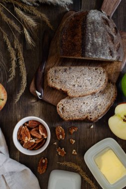 Kahvaltı masasının üst görüntüsü, ev yapımı tahıl ekmeği, tereyağı, fındık fındıklı koyu ahşap arka plan, kopyalama alanı.