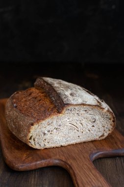 Koyu arkaplanda ev yapımı tahıllı ekşi ekmeği kapat, boşluğu kopyala