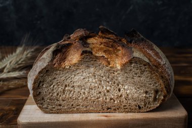 Koyu arkaplanda ev yapımı tahıllı ekşi ekmeği kapat, boşluğu kopyala