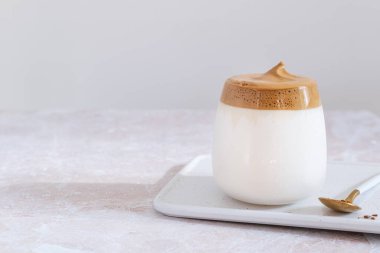 Moda Kore buzlu dalgona kahvesi, pembe mermer masada çırpılmış kahve.