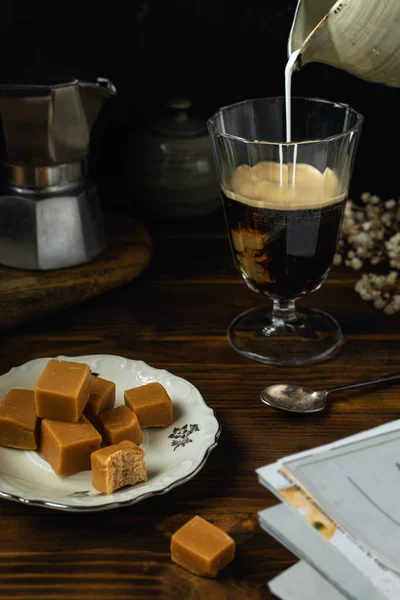 将咖啡杯与一些盐渍焦糖软糖 莫卡咖啡搅拌器放在深色木制桌子上的特写 — 图库照片