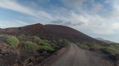 Kamera bir off-road aracının önüne bağlı ve dağ manzaralı yoldan geçiyor.