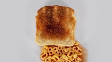 spagetti mektupları beyaz tabakta kızarmış ekmeğin üzerinde kalır. 