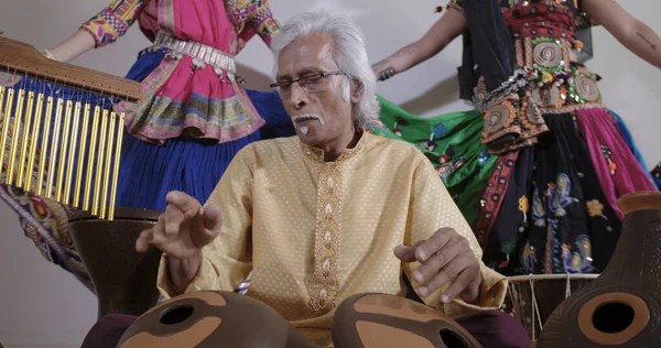 Hombre tocando la batería india con bailarinas . —  Fotos de Stock